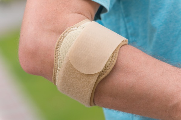 Sport injury treated by Hosford Health Clinic osteopath; man wearing tennis elbow brace