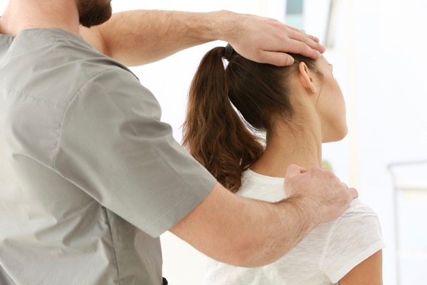 Osteopath stretching a patients neck with headache, neck and shoulder pain